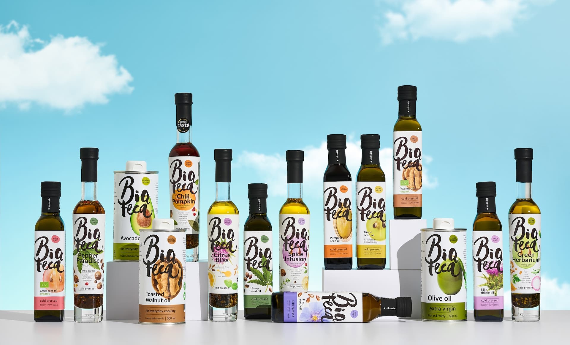 Biateca complete product collection featuring gourmet oils, classic oils, and functional tin packaging against blue sky